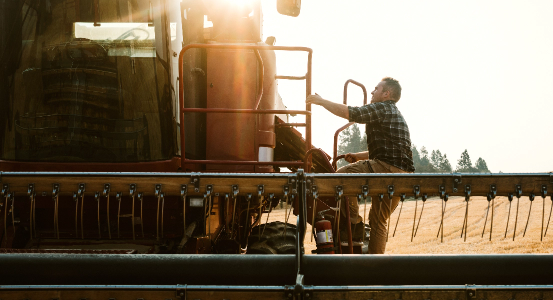 farmer climbing into the cab of a tractor