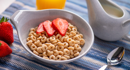 bowl of cereal on a table with sliced strawberries